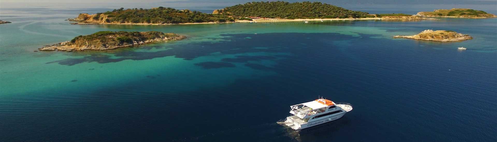 Bateau dans les eaux bleues de Crète avec un magnifique paysage des îles pendant Excursion en bateau vers le Mont Athos et l'île d'Ammouliani avec Eirinikos Glassbottom Daily & Private Cruises.