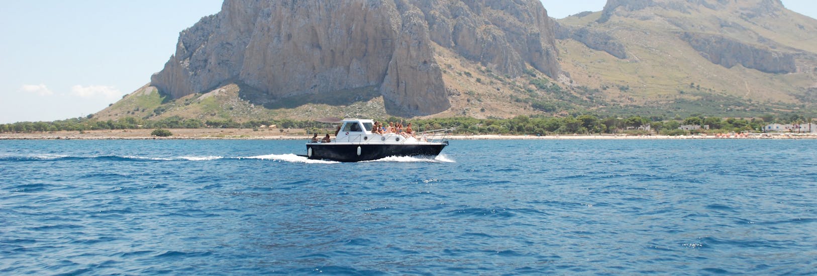 Primero's boat navigating in front of the promontory of San Vito Lo Capo during the Private Boat Trip around San Vito Lo Capo with Lunch and Apéritif with Primero.