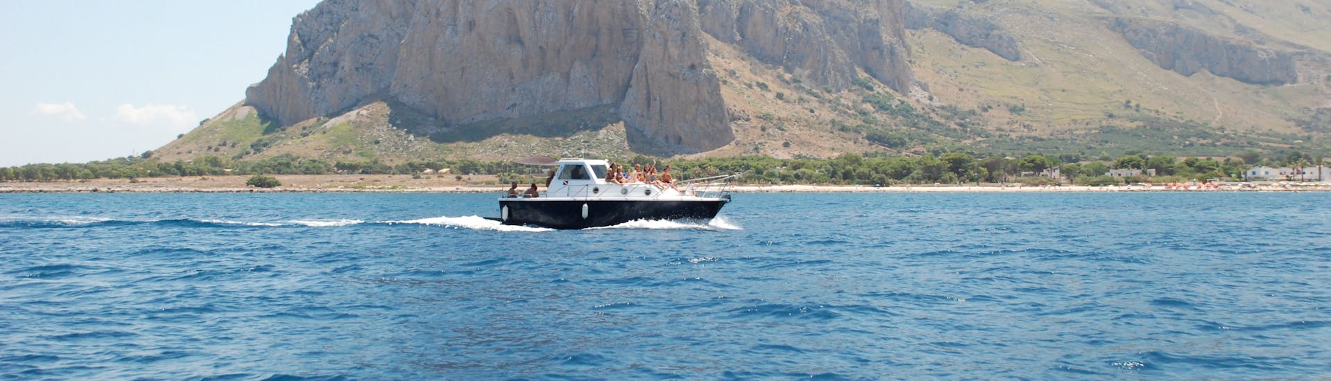Primero's boat navigating in front of the promontory of San Vito Lo Capo during the Private Boat Trip around San Vito Lo Capo with Lunch and Apéritif with Primero.