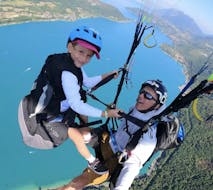 A kid and their instructor during the tandem Paragliding over Lake Annecy - Minipouss & Discovery with K2 Outdoor Annecy.