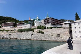 Vista di un monastero del Monte Athos con un monaco che cammina lungo il molo durante il giro in barca al Monte Athos con Eirinikos Glassbottom Cruises Halkidiki.