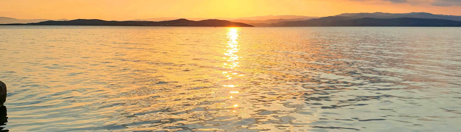 Coucher de soleil sur Halikidiki depuis le bateau lors de Croisière festive en bateau autour de l'île d'Ammouliani avec Eirinikos Glassbottom Daily & Private Cruises.