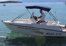 A man is at the commands of the boat during the Boat Rental in Agios Nikolaos (up to 6 people) without Licence with Amoudi Watersports.