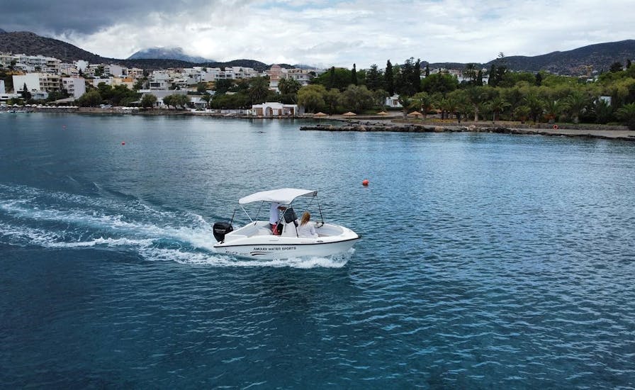 The boat is navigating along the coast during the Boat Rental in Agios Nikolaos (up to 6 people) without Licence with Amoudi Watersports.
