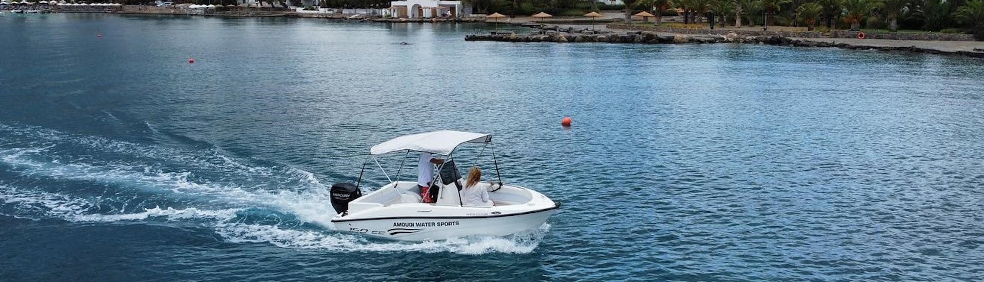 The boat is navigating along the coast during the Boat Rental in Agios Nikolaos (up to 6 people) without Licence with Amoudi Watersports.
