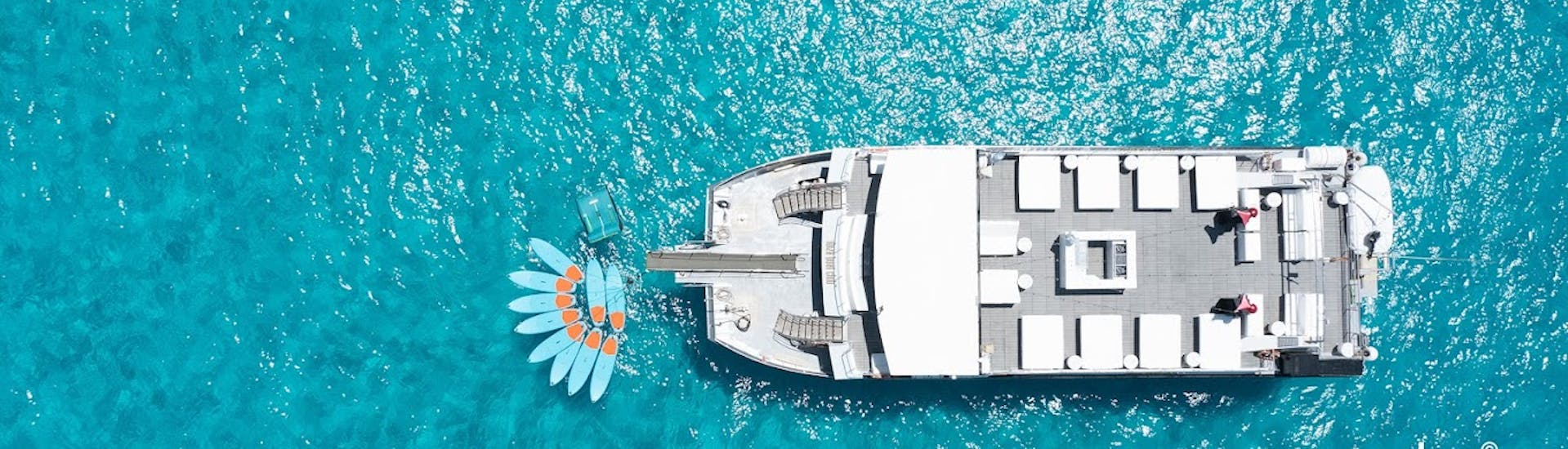 Een grote catamaran die geniet van een bootfeest op Ibiza met open bar en DJ met Ibiza Boat Club.