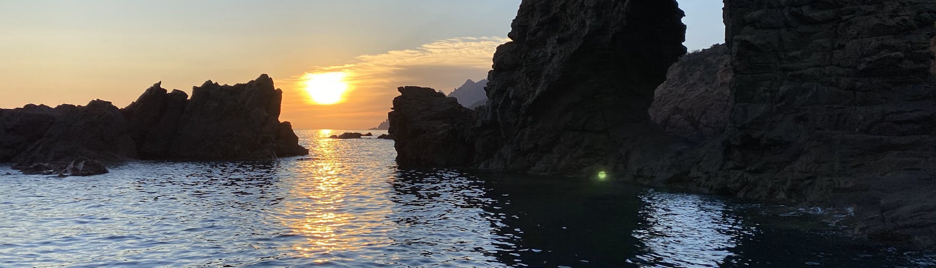 Landscape of the reefs of the gulf of Porto with a beautiful sunrise on the horizon during Boat Trip around the Gulf of Porto with Snorkeling, Towed Buoy and Local Lunch by Avventu Event's Porto.