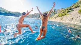 Personen springen ins Wasser bei der Party-Bootstour in Ibiza von Playa d'en Bossa mit DJ mit Magic Boat Party Ibiza.