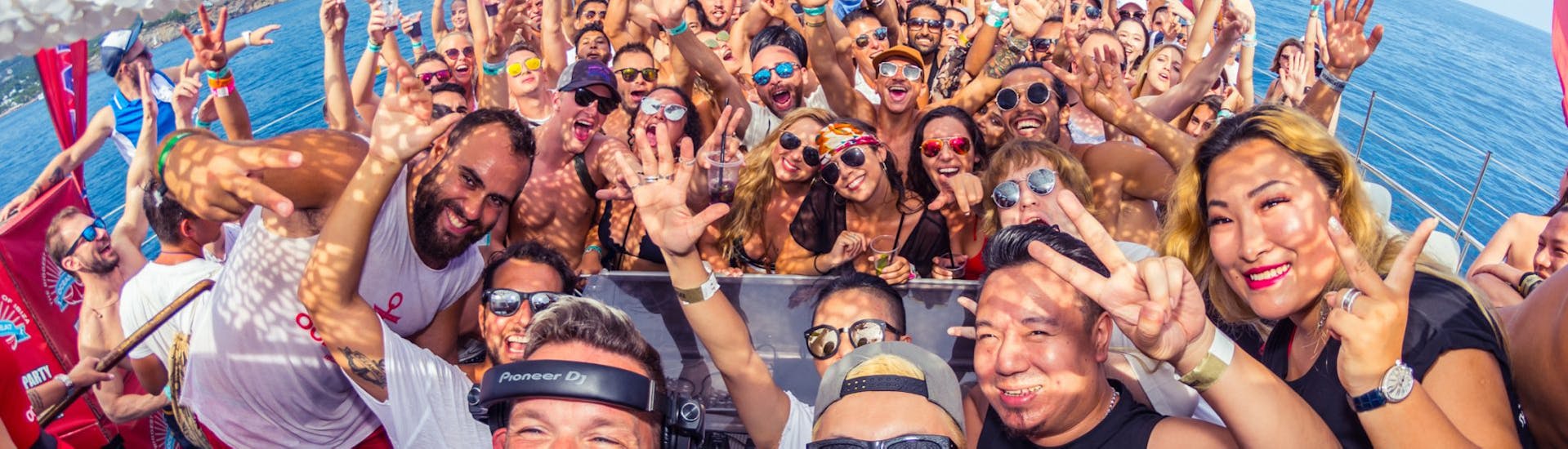 Personen und DJ haben Spaß bei der Party-Bootstour in Ibiza von Playa d'en Bossa mit offener Bar.