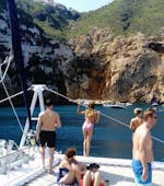 A group of people visit the coves and caves of Calpe during a catamaran trip from Calpe with BBQ & swimming with Mundo Marino.