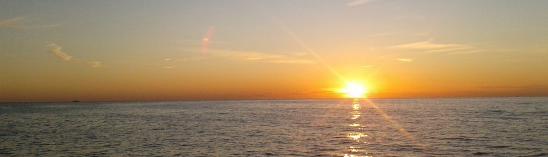 Uitzicht op de ondergaande zon aan de horizon tijdens een catamarantocht bij zonsondergang vanuit Calpe met Cava.