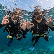 Two divers in the water signaling everything is okay with their hands during Discover Scuba Diving in Ses Salines from Formentera for Beginners by Vellmari Diving Center Formentera.