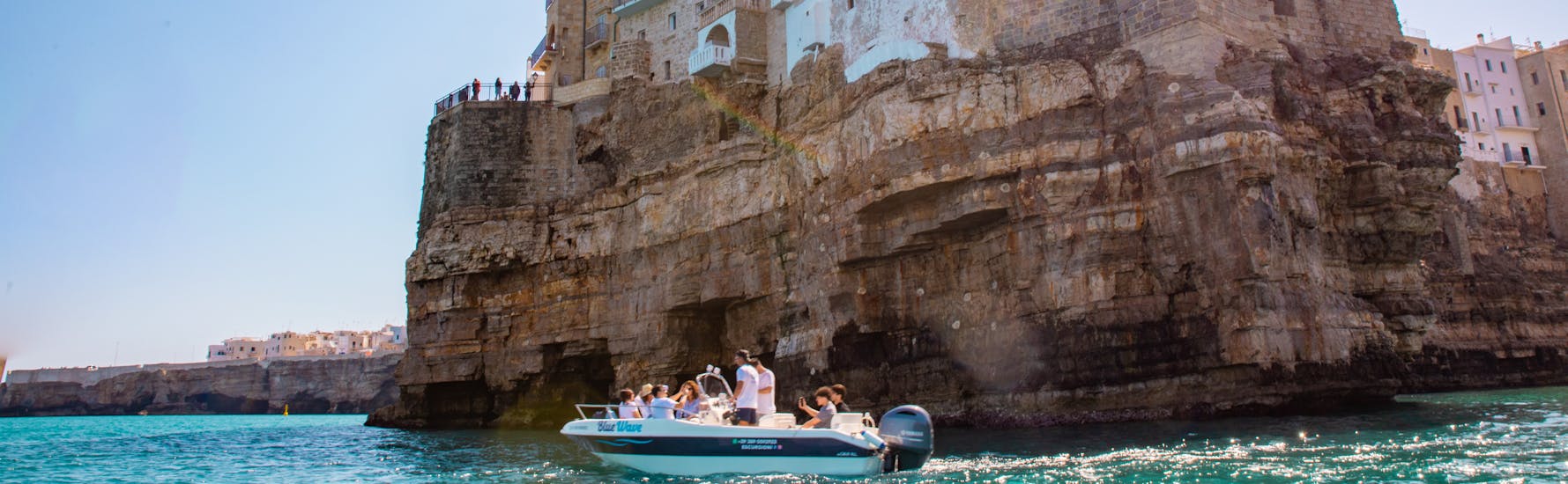 De boot van Blue Wave die Polignano a Mare doorkruist tijdens de Privé Boottocht naar de Grotten van Polignano a Mare met Apéritif.