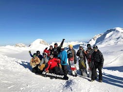 Snowboardlehrer mit seiner Gruppe im Snowboardkurs für alle Levels vor den Bergen in Crans-Montana.