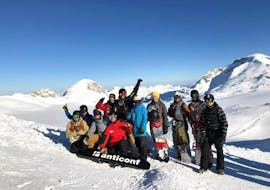 Snowboardlehrer mit seiner Gruppe im Snowboardkurs für alle Levels vor den Bergen in Crans-Montana.