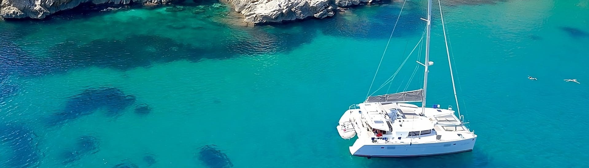 Ein Boot navigiert während der Private Katamarantour von Cala Jondal nach Atlantis & Es Vedrà mit Schnorcheln mit Goa Catamaran Ibiza.