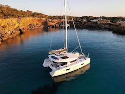 A boat navigating on a full day Private Catamaran trip from San Antonio to Cala Salada with Snorkeling with Goa Catamaran Ibiza.