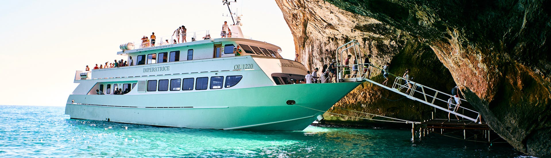 Das Motorboot, das vom Nuovo Consorzio Trasporti Marittimi eingesetzt wird, legt in Grotta del Fico während der Tagesbootstour von La Caletta zum Golf von Oresei mit Schwimmstopps