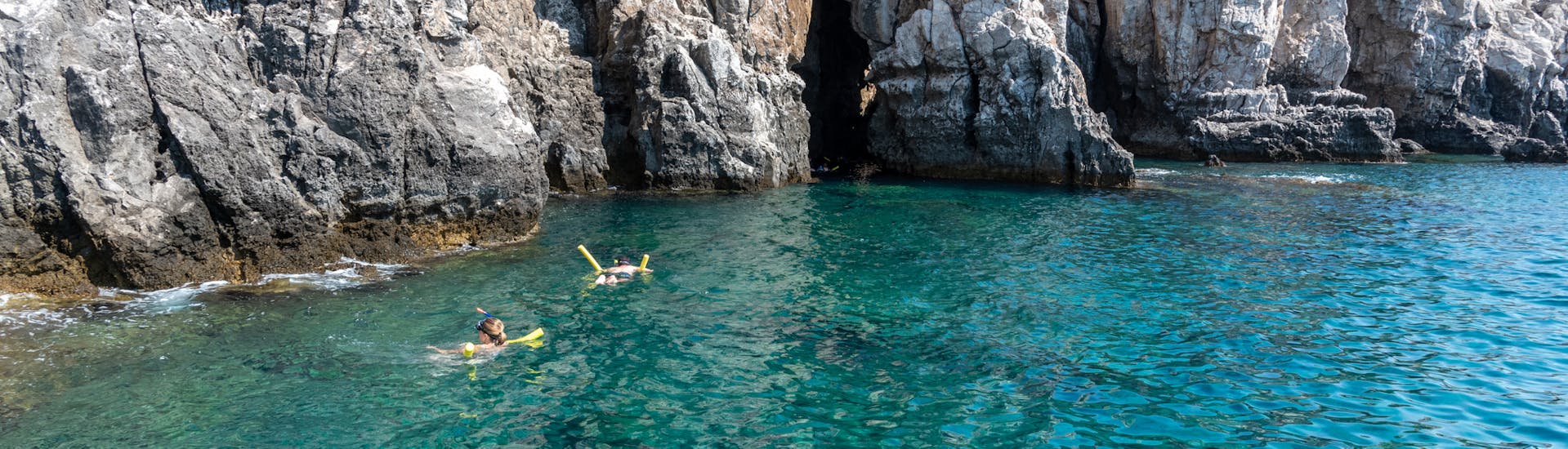 Personen die vor der Traganou Höhle schwimmen während der Bootstour von Faliraki zur Anthony Quinn Bay mit Schnorcheln mit Sofia Sea Cruises Faliraki.