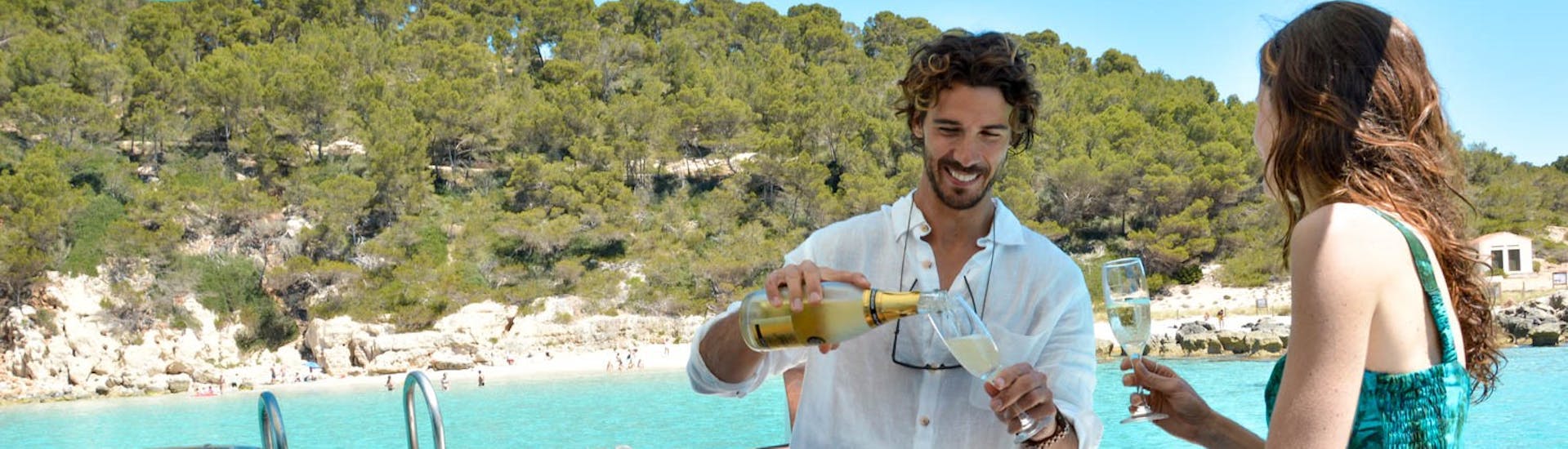 Hombre y mujer bebiendo champán en el paseo en barco privado de Cala Galdana a Cala en Turqueta con aperitivo y buceo.