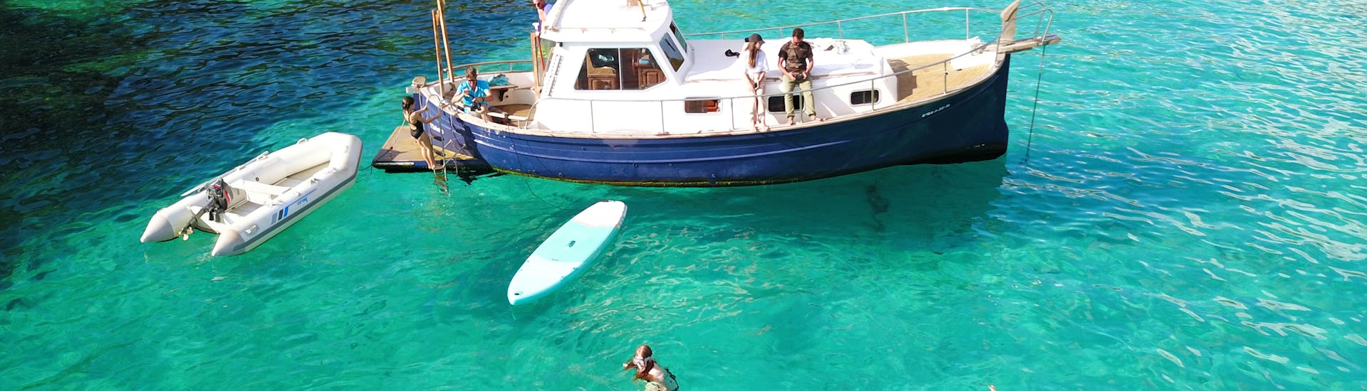 Gente divirtiéndose en aguas turquesas durante el paseo privado en barco desde Cala Galdana con esnórquel y SUP.