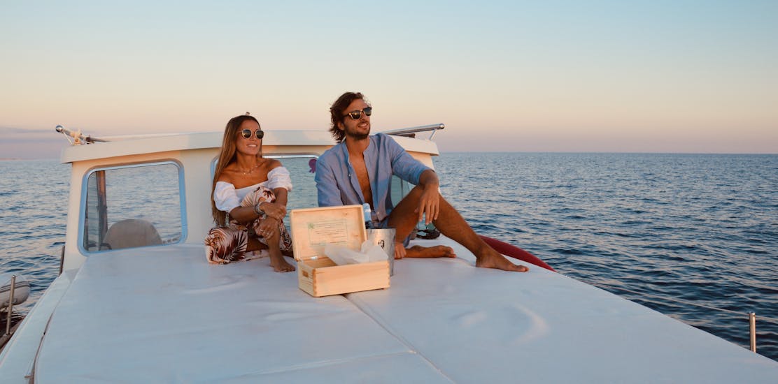 Mann und Frau sehen sich auf dem Sonnendeck den Sonnenuntergang an am Ende der Privaten Ganztägigen Bootstour von Cala Galdana mit Sonnenuntergang & Schnorcheln & SUP.