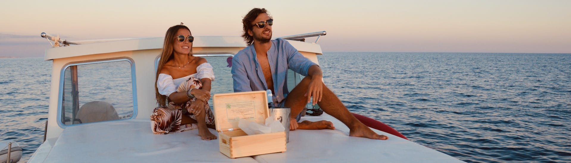 Una coppia guarda il tramonto durante la Gita in barca privata al tramonto da Cala Galdana con snorkeling e SUP con Marenostrum Menorca.