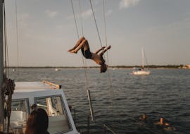 Eine Person springt ins Wasser bei der Privaten Bootstour von Alghero bei Sonnenuntergang mit Apértitif mit Escursioni in Barca Alghero.