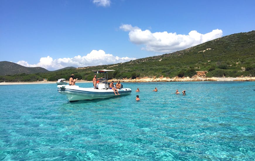 Personen schwimmen im klaren Wasser um das Boot während der RIB-Bootstour von Cagliari zum Poetto Strand mit Schnorcheln.