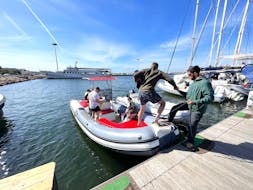 De schipper van Blue Rent Boat Cagliari helpt een aantal deelnemers aan boord tijdens de Privé RIB boottocht in de Golf van Cagliari met stop op Poetto Beach met Blue Rent Boat Cagliari.