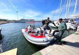 Lo skipper di Blue Rent Boat Cagliari aiuta alcuni partecipanti ad imbarcare durante il Giro in gommone privato nel Golfo di Cagliari con sosta alla Spiaggia del Poetto.