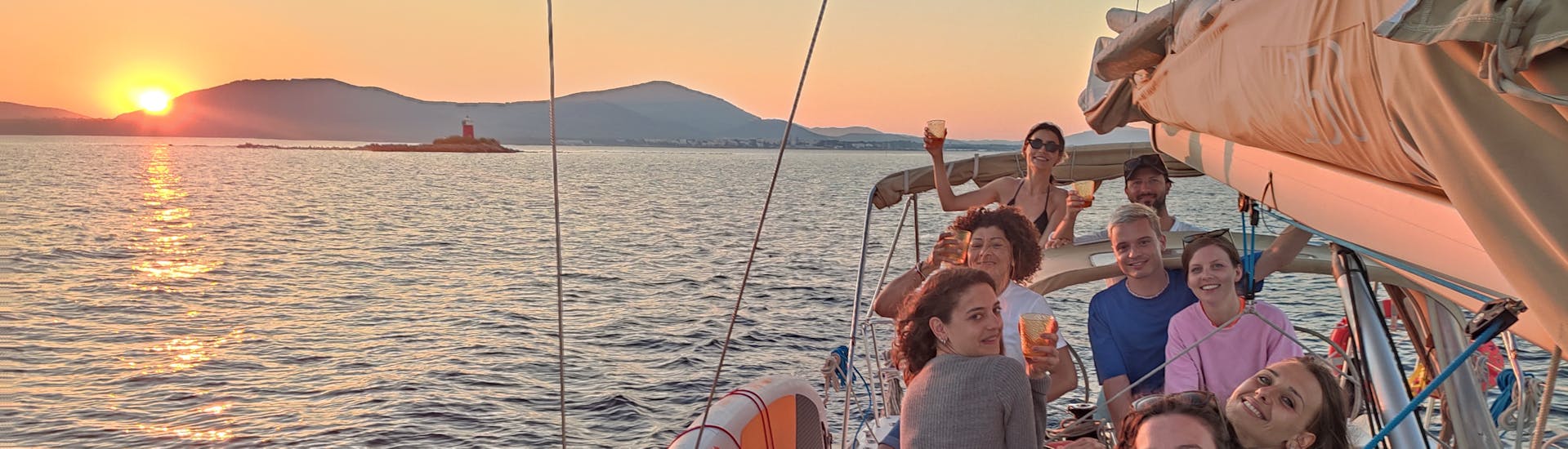 Gente disfrutando de la puesta de sol Paseo en barco de vela alrededor de Alghero con aperitivo con Cruise Sail Charter Alghero.