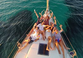 Mensen vermaken zich tijdens de privé zeiltocht bij zonsondergang rond Alghero met aperitief met Cruise Sail Charter Alghero.