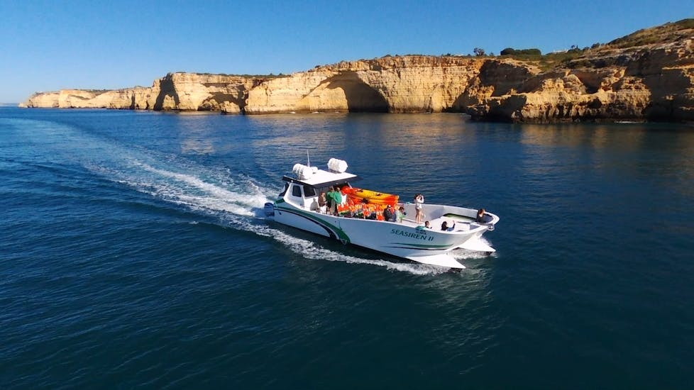 Katamaran fährt herum während der Privaten Katamarantour zu den Benagil Höhlen & Marinha Strand mit Kayaking mit Seasiren Tours Algarve.