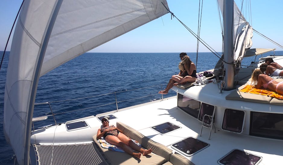 Some participants are enjoying the sun during the Sunset Catamaran Trip in the Gulf of Alghero with Apéritif & Snorkeling with All Sailing Alghero.