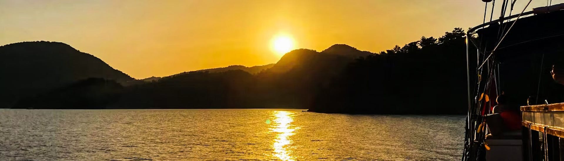 Die Sonne wenn sie unter den Horizont sinkt während der Bootstour von Mandraki zu Kallithea Springs mit Schnorcheln bei Sonnenuntergang mit Royal Sailing Rhodes.