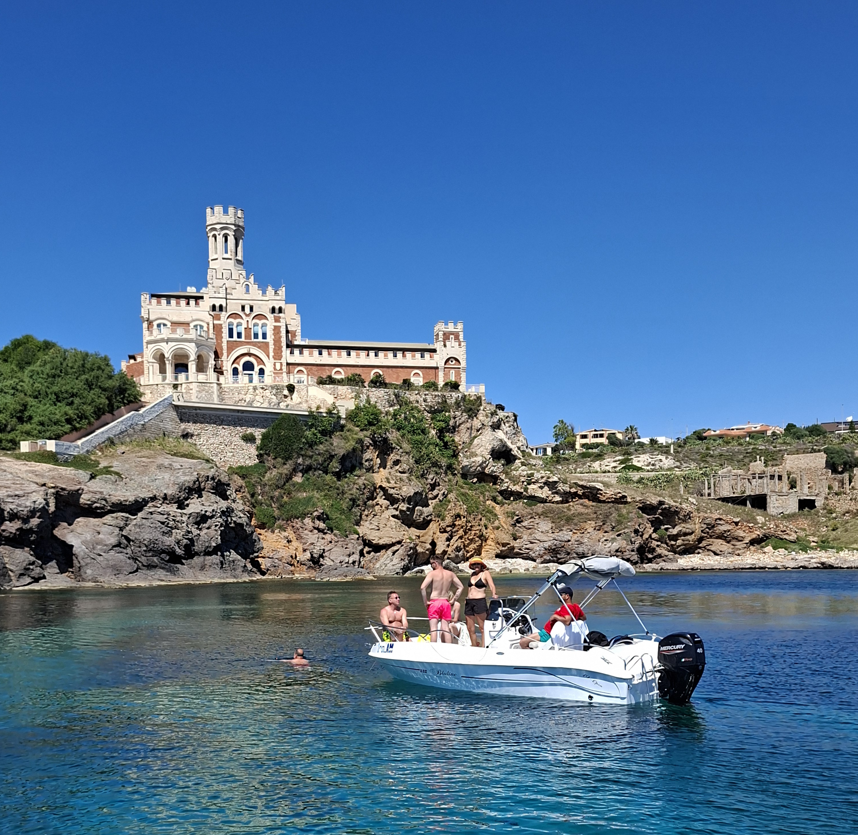 Eine Bootstourgruppe schwimmt an einer historischen Küstenburg vorbei. Eine Gruppe von Menschen ankert auf einem privaten Bootsausflug von Avola nach Marzamemi mit Schnorchelmöglichkeit, der von Ioniam Rent Boat Avola angeboten wird, im türkisfarbenen Wasser vor einer Küstenburg.