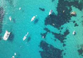 Vogelperspektive von vielen Booten im türkisen Wasser, wo Ihr während Eurer ganztägiger Bootstour von Ibiza Stadt nach Es Vedrá & Formentera mit Paella & Sonnenuntergang mit Excursiones Ibizahalten werdet.