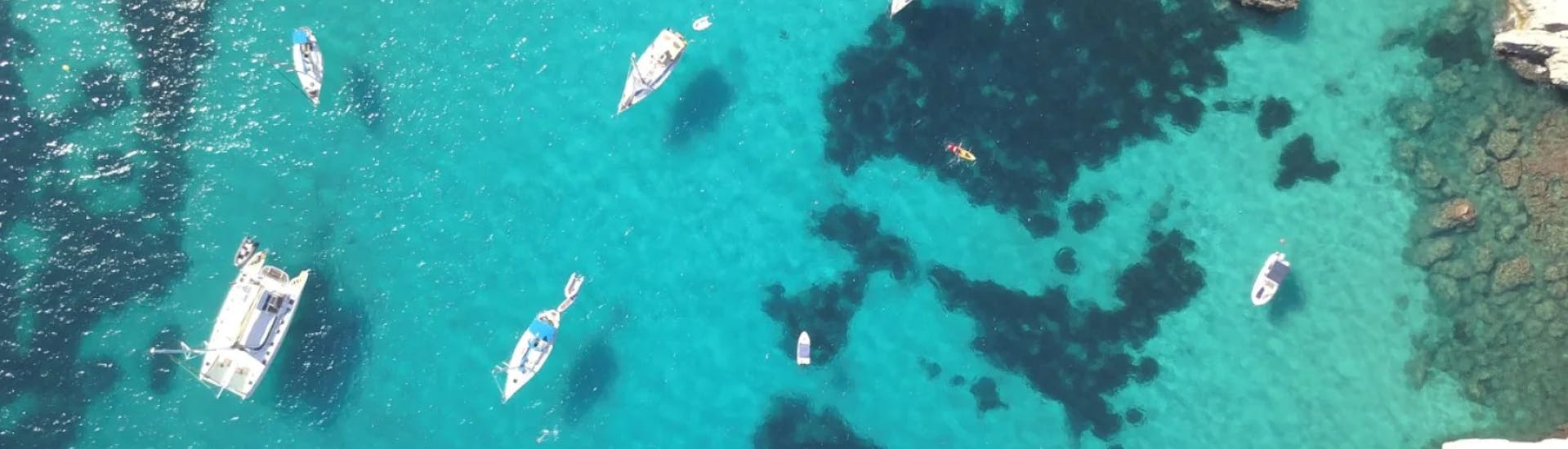 Vogelperspektive von vielen Booten im türkisen Wasser, wo Ihr während Eurer ganztägiger Bootstour von Ibiza Stadt nach Es Vedrá & Formentera mit Paella & Sonnenuntergang mit Excursiones Ibizahalten werdet.