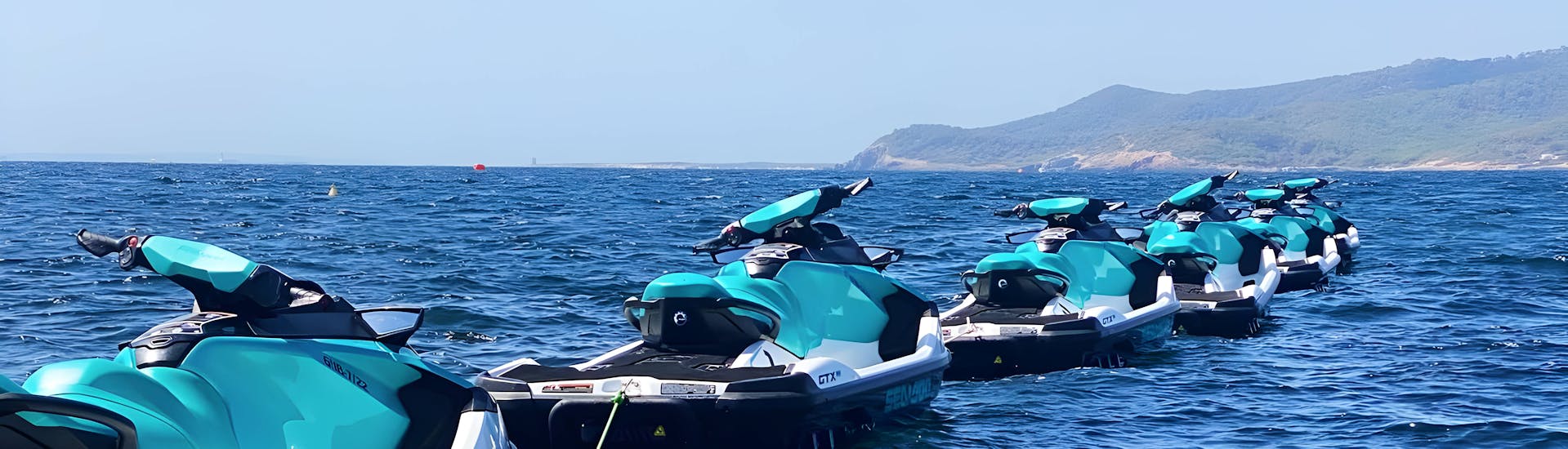 Una flota de motos de agua aparcadas en el mar durante un emocionante tour en Ibiza, explorando la Playa d'en Bossa y Santa Eulalia con Enjoy Watersports Ibiza.