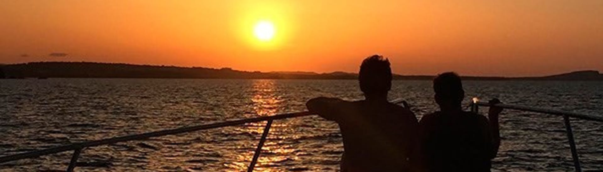 Boot im Wasser bei Sonnenuntergang währen der privatn Bootstour von Fornells mit Badestopps & Sonnenuntergang.