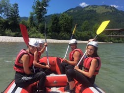 A group sitting in a raft on the river during their Rafting on the Kitzbüheler Ache for Families with Der Guide Brixtental.
