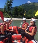 Un groupe assis dans un radeau sur la rivière pendant leur Rafting sur le Kitzbüheler Ache pour les familles avec Der Guide Brixtental.
