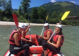 Un grupo sentado en una balsa en el río durante su Rafting en el Kitzbüheler Ache para familias con Der Guide Brixtental.