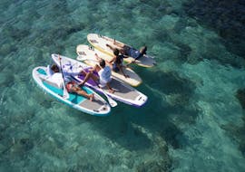 Algunas personas descansando en su tabla de SUP en Formentera durante una excursión guiada en SUP por la Bahía de Es Pujols en Formentera con Wet4Fun Formentera.