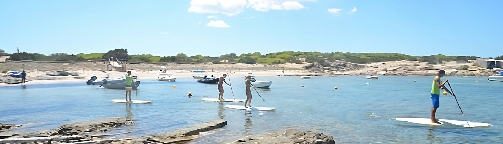 Gente disfrutando de un día de SUP en Formentera durante la excursión guiada de SUP en la Bahía de Es Pujols en Formentera con Wet4Fun.