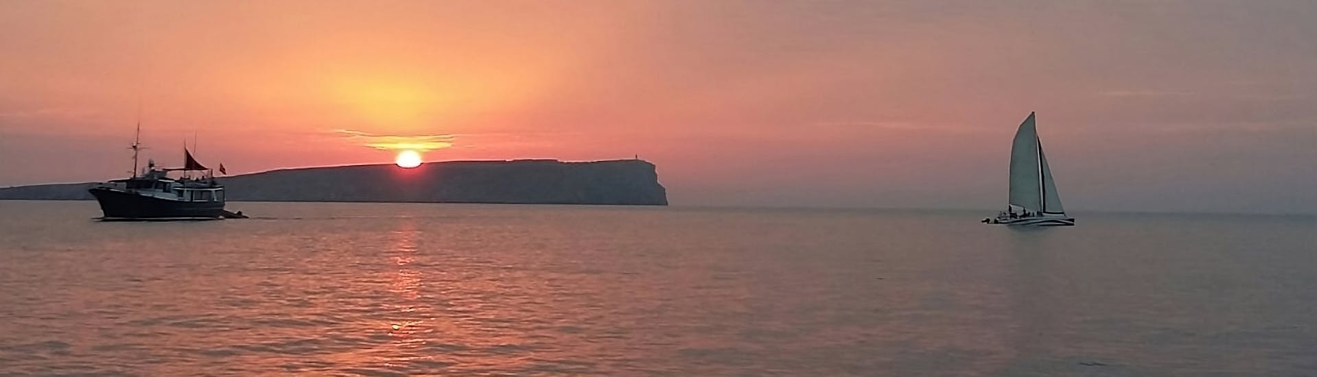 The view of the sunset you can see with Katayak Menorca during a sunset catamaran trip from Fornells with open bar.