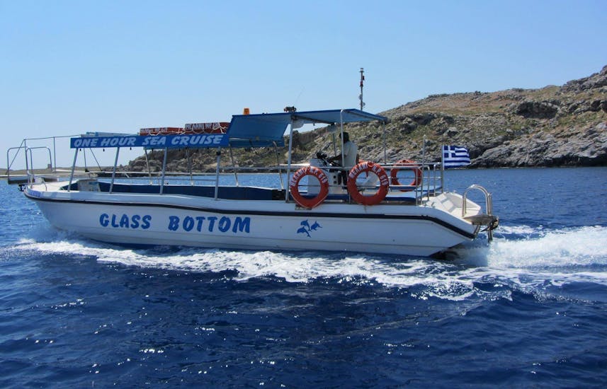The boat is navigating during the Glass-Bottom Boat Trip around Lindos Coast with Swimming at the Red Sand Beach.