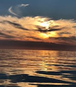 La hermosa puesta de sol durante el Paseo privado en barco con fondo de cristal al atardecer desde Lindos con baño en la bahía de Navarone.