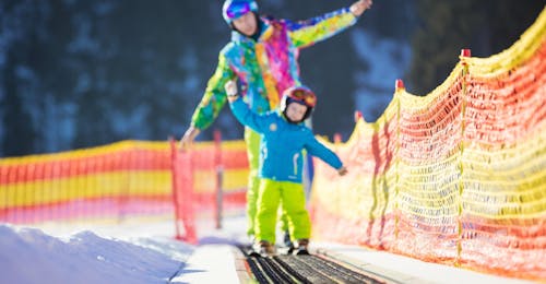Private Ski Lessons for Kids of All Levels from Ski School Evolution 2 Avoriaz An instructor accompanies a young skier on the magic carpet during private ski lessons for kids with the ski school Evolution 2 Avoriaz.